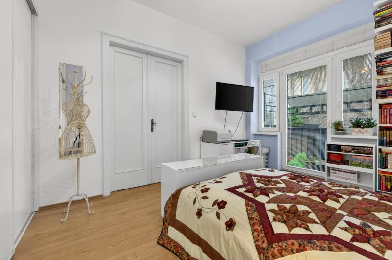 Schlafzimmer in einer 3-Zimmer-Wohnung mit Bett, Regalen und Boden mit Holzdekor.