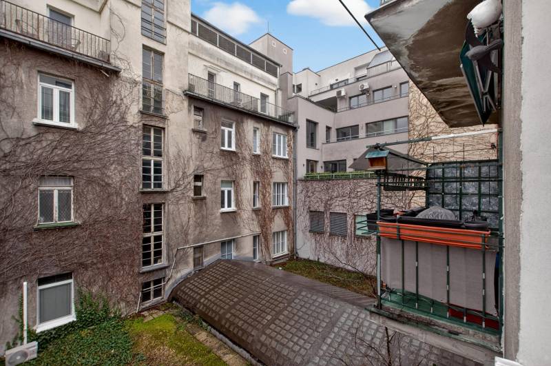 Blick auf den Innenhof von Wohnhäusern mit alter Putzfassade und Balkon.