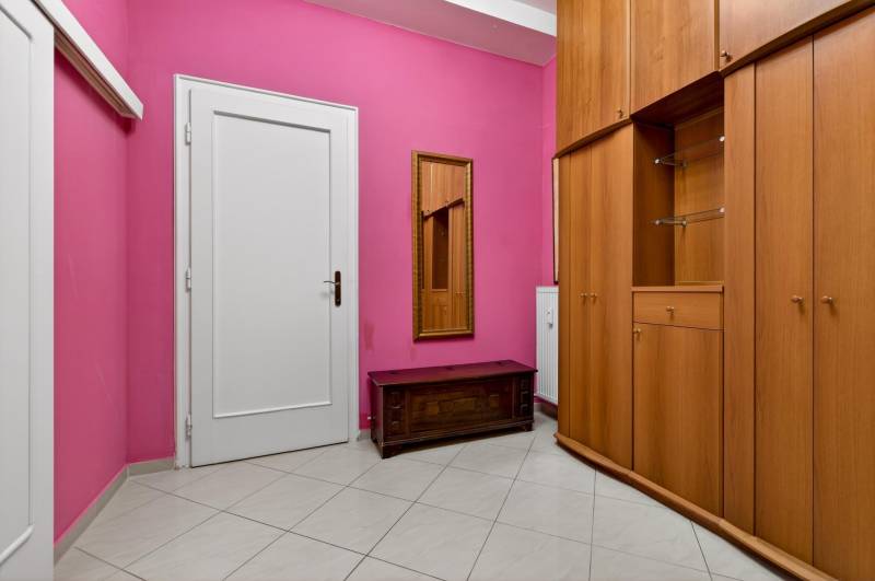 Der Flur in einer 3-Zimmer-Wohnung mit rosa Wänden, weißen Türen und einem Kleiderschrank.