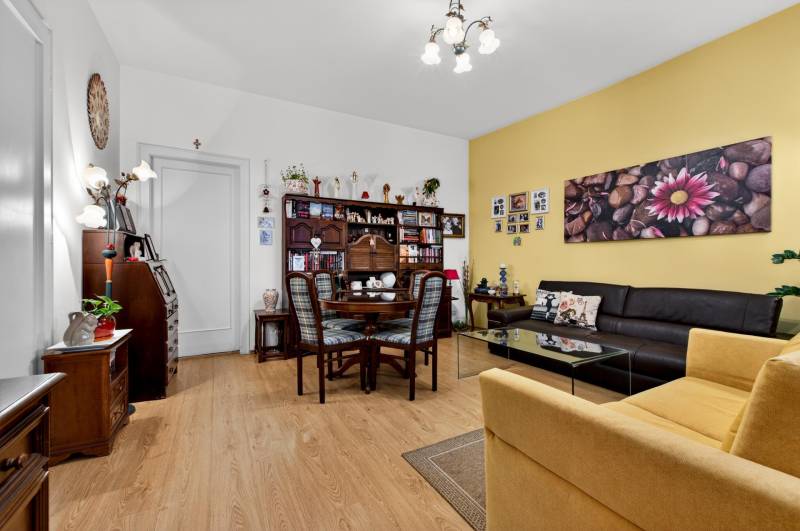 Wohnzimmer mit Holzboden, Bildern, dunkelbraunem Sofa und Esstisch.