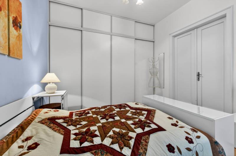 Schlafzimmer mit dekorativer Steppdecke in einer 3-Zimmer-Wohnung mit minimalistischer Einrichtung.