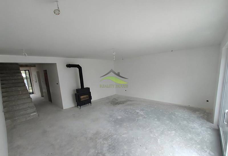 Innenraum eines Einfamilienhauses mit Kamin und Treppe, wartet auf Fertigstellung.