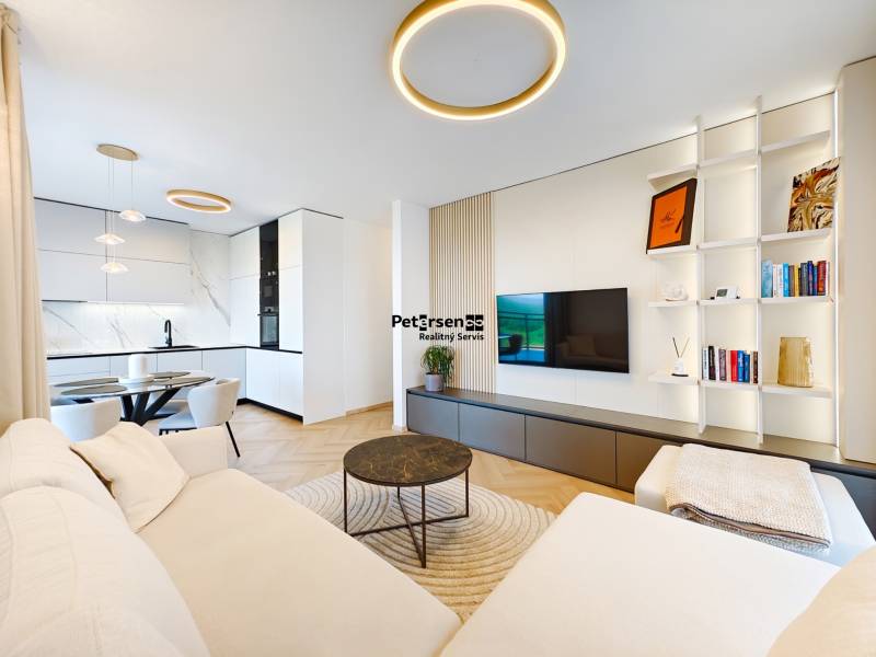 Wohnzimmer einer Zweizimmerwohnung mit Sofa, Küche und Holzboden.