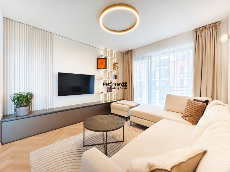 Wohnzimmer in einer Zweizimmerwohnung mit Sofa, Fernseher und Boden in Holzoptik.