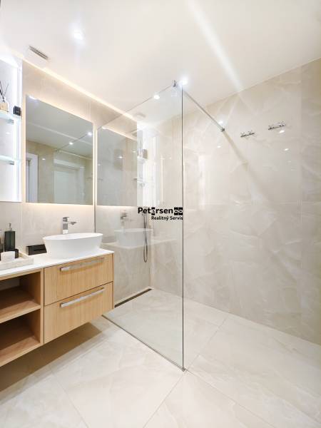 Badezimmer in einer 2-Zimmer-Wohnung mit großem Spiegel und Duschkabine aus Glas.