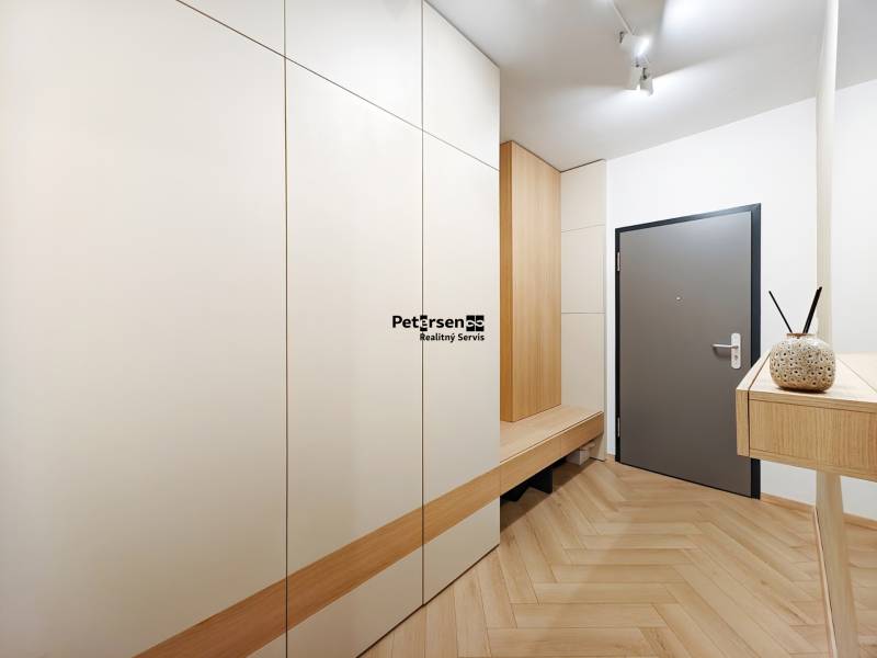 Eingangsflur mit Holzboden in einer 2-Zimmer-Wohnung mit weißen Schränken.