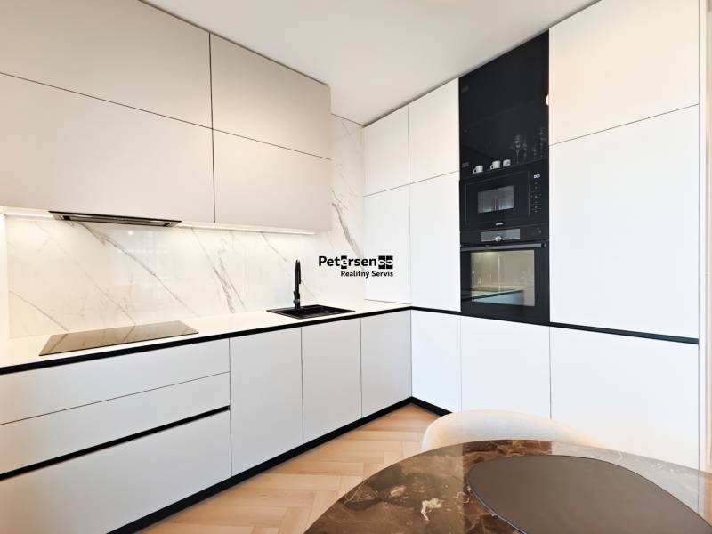 Küche in einer 2-Zimmer-Wohnung mit weißen Schränken und einem Boden in Holzoptik.