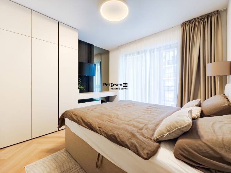 Schlafzimmer in einer 2-Zimmer-Wohnung mit Holzboden, großem Schrank und Vorhängen.