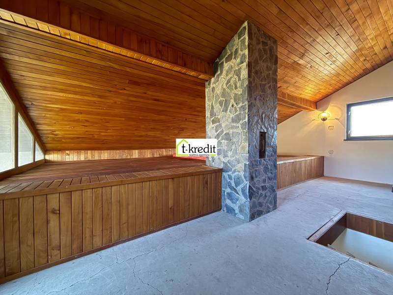 Ein Dachzimmer mit Holzverkleidung und einem Steinkamin in einer Berghütte.