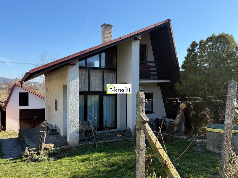 Eine Hütte in Zlaté Moravce mit einem Holzzaun, Rasen und Bäumen in der Umgebung.