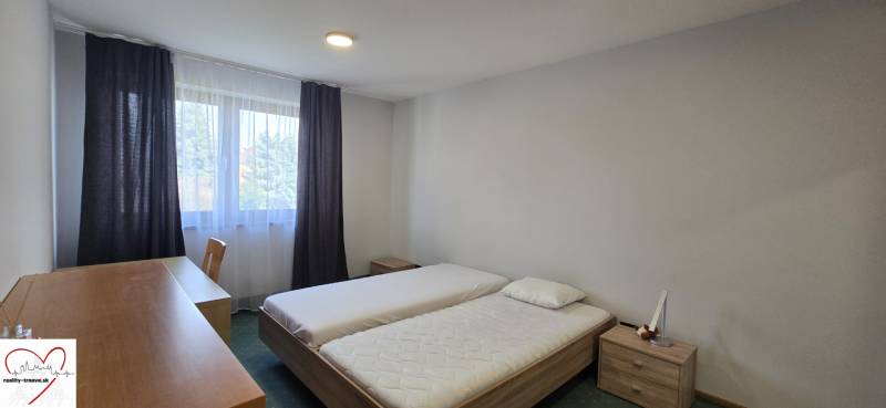 Schlafzimmer mit zwei Betten, Schreibtisch und Fenster in einer 3-Zimmer-Wohnung.