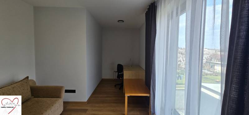 Izba v 3-izbovom byte s podlahou s dreveným dekorom, stolom a pohovkou.