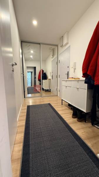 Flur einer 4-Zimmer-Wohnung mit Holzboden und großem Spiegel.
