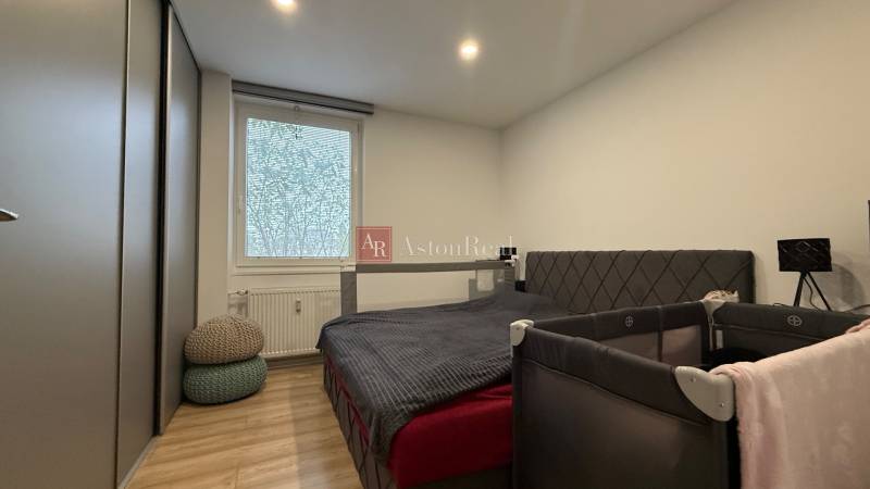 Schlafzimmer in einer 4-Zimmer-Wohnung mit Bett, Schrank und Holzdekor auf dem Boden.