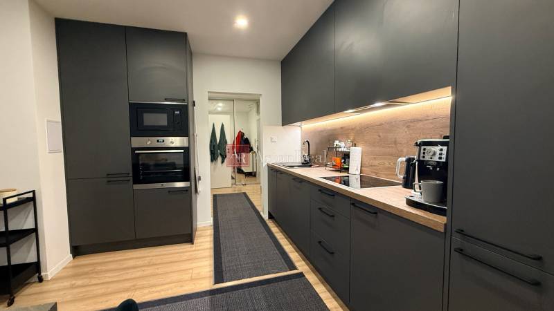 Küche in einer 4-Zimmer-Wohnung mit dunklen Schränken und einem Holzboden.