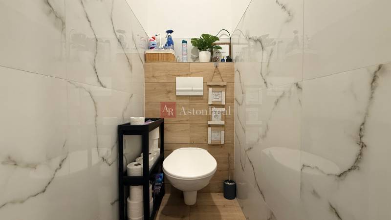 Badezimmer mit hängendem WC, Holzdekor und Regal in einer 4-Zimmer-Wohnung.