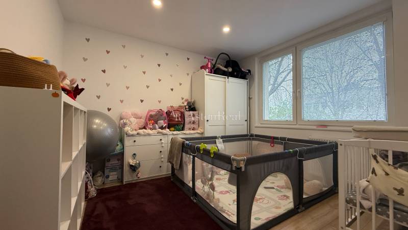 Kinderzimmer in einer 4-Zimmer-Wohnung mit einem Spielgitter und weißen Möbeln.
