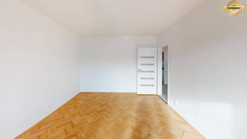 Ein weißer Raum mit einem Boden in Holzoptik und weißen Türen in einer 2-Zimmer-Wohnung.