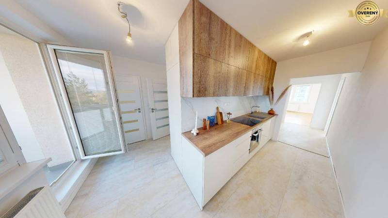Küche in einer 2-Zimmer-Wohnung mit hellem Boden und Schränken in Holzoptik.