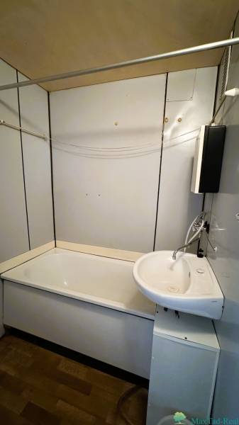 Badezimmer in einer 3-Zimmer-Wohnung mit Badewanne, Waschbecken, einfachen Fliesen und einem Badezimmerschrank.