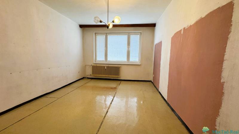 Das Zimmer in der 3-Zimmer-Wohnung hat einen Boden mit Holzdekor-Effekt und einen Heizkörper.