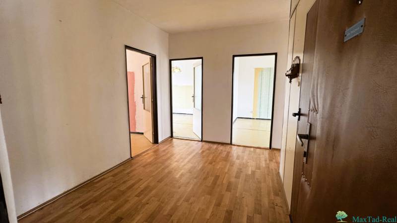 Eingangsbereich in einer 3-Zimmer-Wohnung mit Holzboden und mehreren Türen.