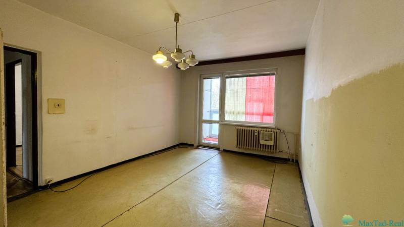 Ein Zimmer in einer 3-Zimmer-Wohnung mit Balkon, einfache Wände und Beleuchtung.