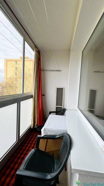 Eine verglaste Loggia in einer 3-Zimmer-Wohnung mit einem Tisch und einem Plastikstuhl.