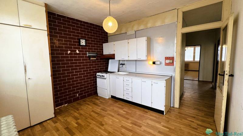 Küche in einer 3-Zimmer-Wohnung mit weißen Schränken und einem Boden in Holzoptik.