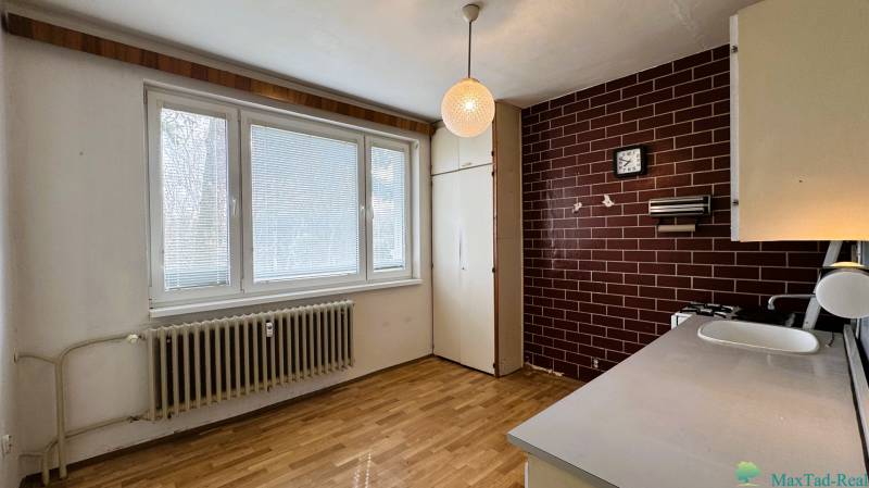 Küche mit Holzboden in einer 3-Zimmer-Wohnung mit braunen Fliesen.