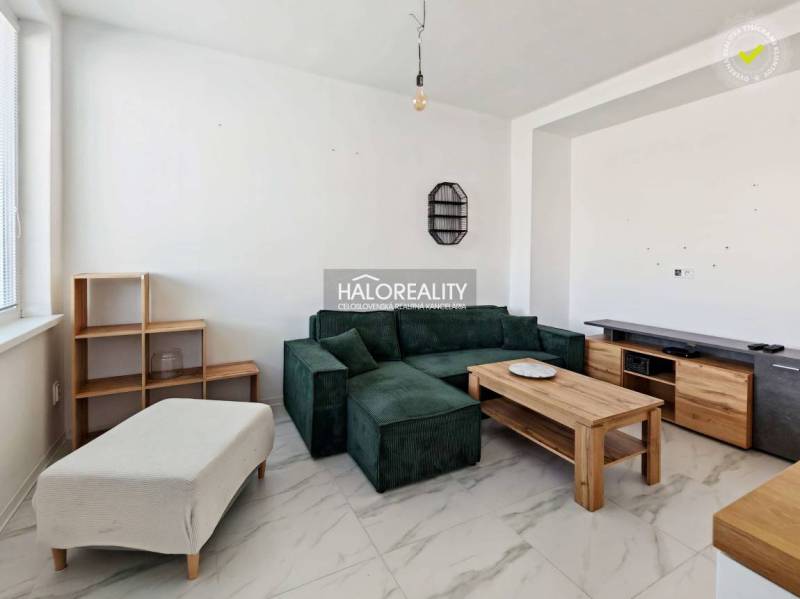 Wohnzimmer mit dunklem Sofa in einer 3-Zimmer-Wohnung mit Fliesenboden und Holzmöbeldekor.