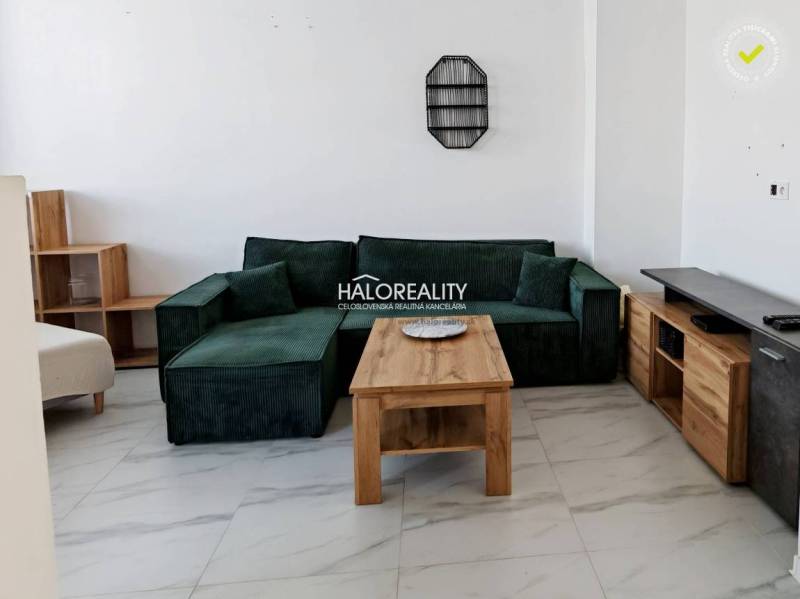 Wohnzimmer in einer 3-Zimmer-Wohnung mit einem grünen Sofa und einem Holztisch.