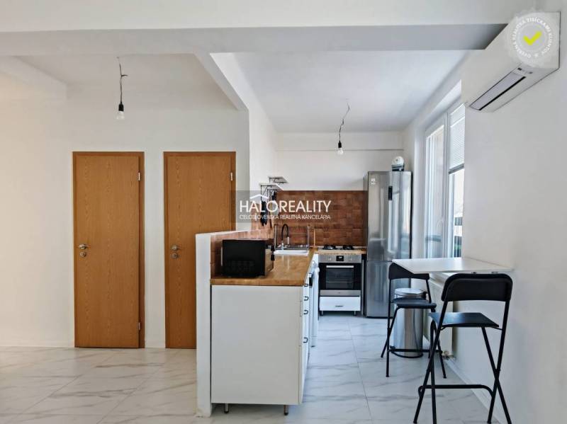 Küche in einer 3-Zimmer-Wohnung mit weißen Wänden und Geräten, Boden mit weißem Dekor.