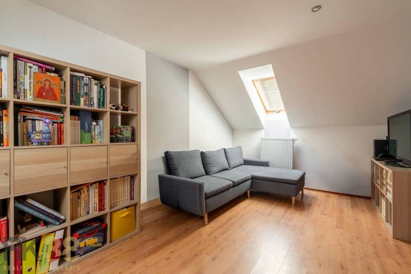 Wohnzimmer mit Ecksofa, Bücherregal und Holzboden in einem Einfamilienhaus.