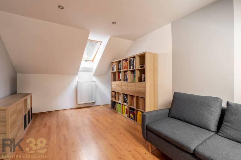 Ein Dachzimmer in einem Einfamilienhaus mit einem Boden in Holzoptik und einem bequemen Sofa.