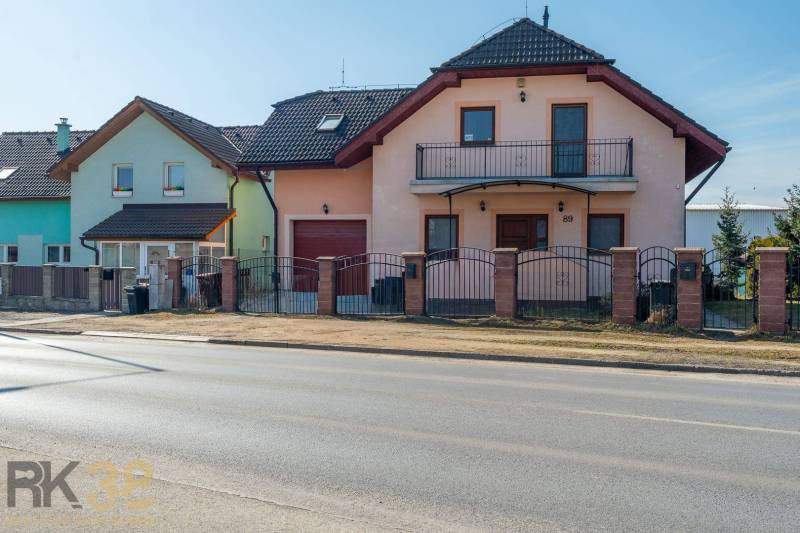 Ein Einfamilienhaus in Poprad mit zwei Etagen, einer Garage und einem Balkon, mit einem Zaun aus Ziegeln.