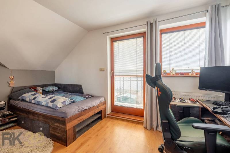 Ein Zimmer mit Bett, Schreibtisch und Stuhl; Boden mit Holzdekor.