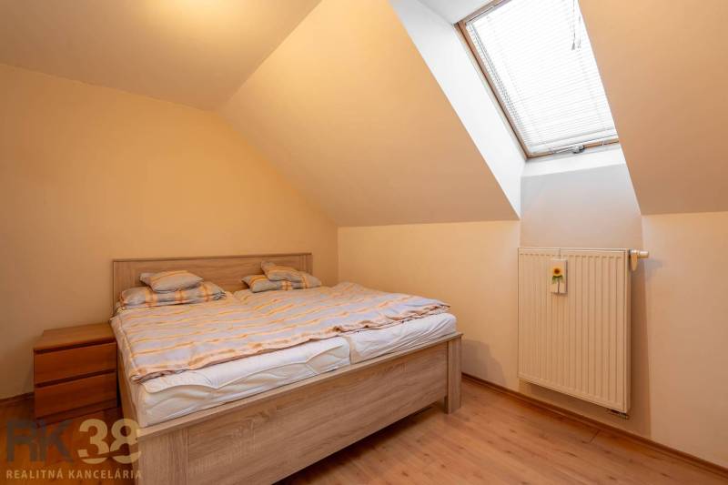 Helles Schlafzimmer in einem Einfamilienhaus mit Doppelbett und Dachfenster.