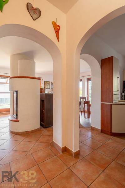 Innenraum eines Einfamilienhauses mit Ziegelboden, bogenförmigen Durchgängen und einem weißen Kamin.