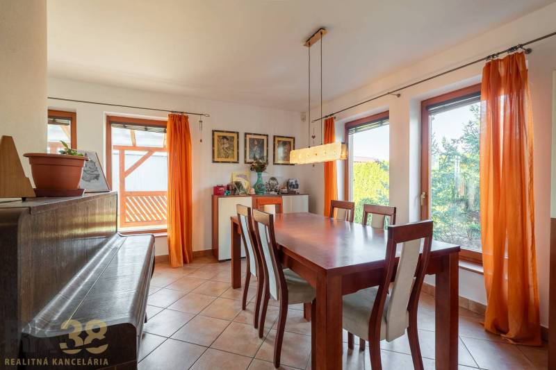 Esszimmer mit großem Tisch, Stühlen und Klavier.