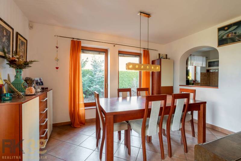 Elfteilige Essgruppe in einem Einfamilienhaus mit orangefarbenen Vorhängen und Fliesen.