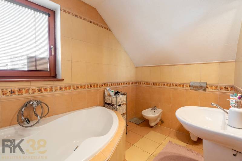 Badezimmer in einem Einfamilienhaus mit Badewanne, Bidet und Fenster mit Jalousien.