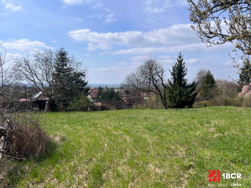 Grünflächen auf Grundstücken - Wohnen in Marianka in der Budovateľská Straße, umgeben von Bäumen und nahegelegenen Häusern.