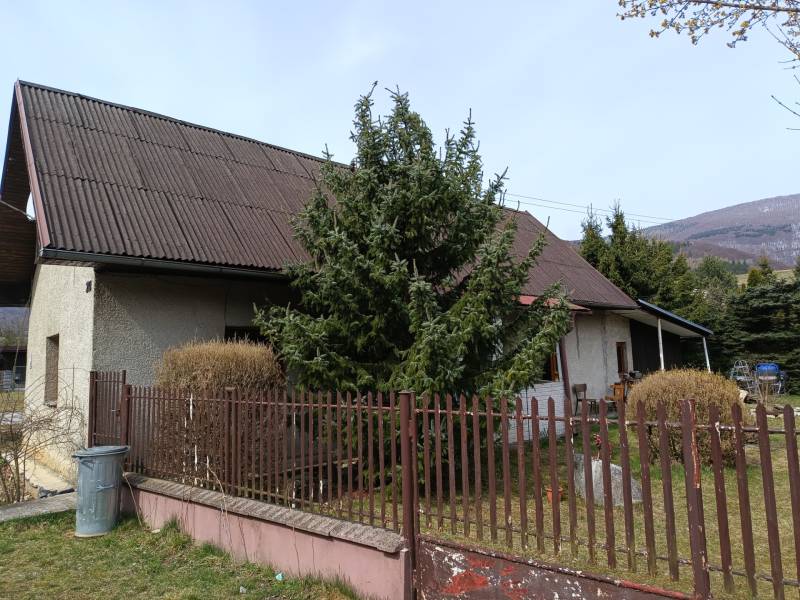 Ein Einfamilienhaus in Vrícko mit einem eingezäunten Garten bei einem Nadelbaum.
