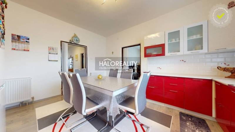 Esszimmer mit roter Küchenzeile und Holzboden in einem Einfamilienhaus.