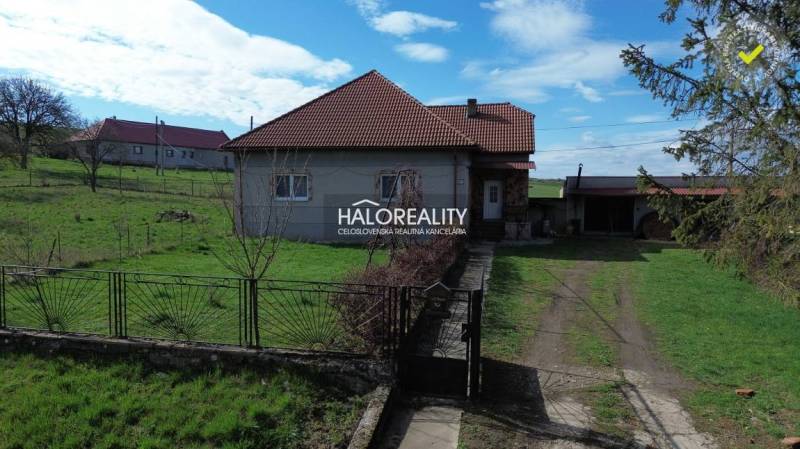 Ein Einfamilienhaus in Rimavské Janovce auf einem Grundstück mit grünem Rasen und Umzäunung.