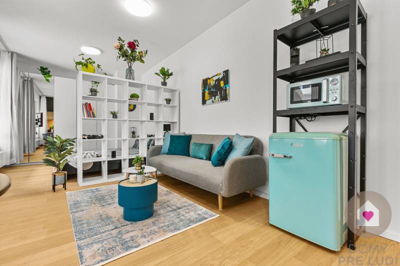 Ein stilvoller Wohnbereich in einer Einzimmerwohnung mit Holzboden, Dekorationen und Pflanzen.