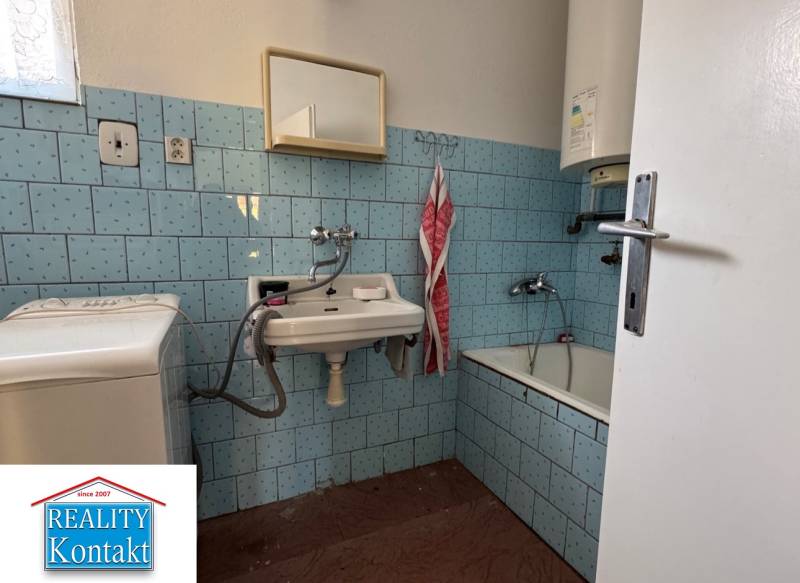 Ein Badezimmer in einem Einfamilienhaus mit blauen Fliesen und einer Badewanne.