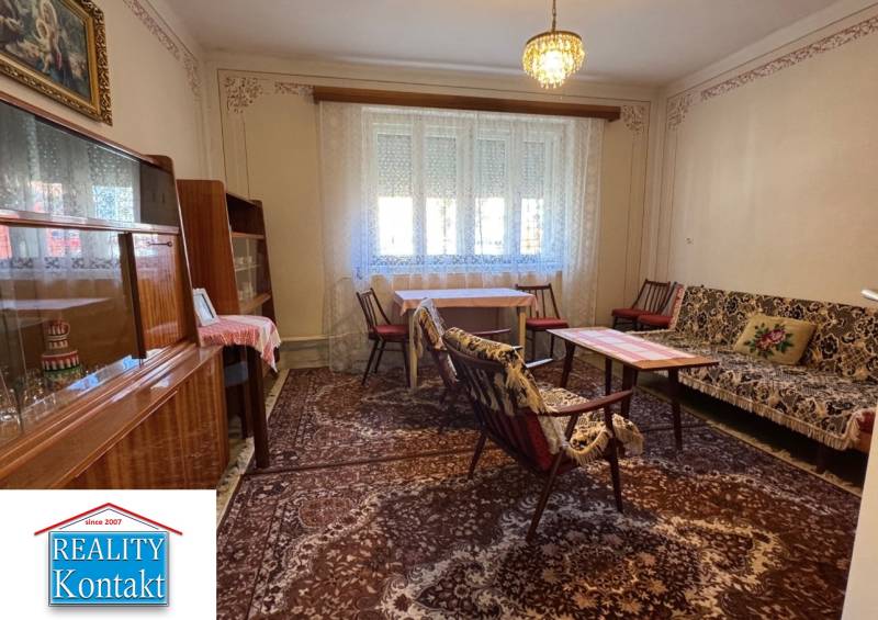 Wohnzimmer in einem Einfamilienhaus mit Teppich, Möbeln und Kronleuchter, Vorhänge an den Fenstern.