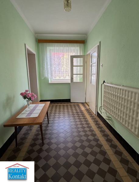 Ein Flur in einem Einfamilienhaus mit Blumen auf dem Tisch und einem gefliesten Boden.